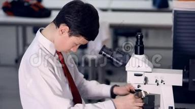10-11岁的小学生在学校实验室里看显微镜，做生物学研究。