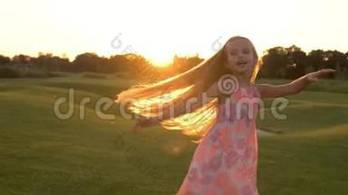 可爱的小女孩在草地上跳舞。