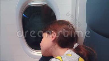 <strong>航空飞机</strong>概念。 坐在窗边的小女孩睡在飞机上。 夜间飞行生活方式