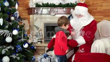 圣诞老人欢迎小男孩，孩子得到圣诞礼物坐在圣诞老人腿上，送给孩子礼物