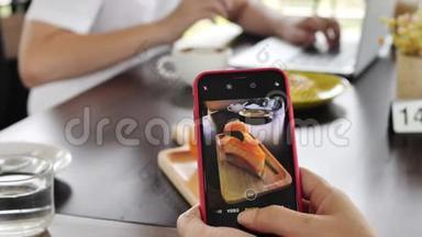 时髦的家庭母子在一家餐馆用手机相机制作食物照片。