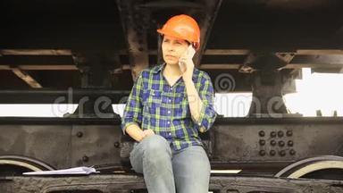 一名女铁路工人坐在一辆货车的运行齿轮的框架上。