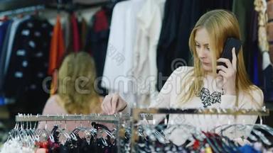 很好的购物和电话聊天。 3.年轻女子在女装`服装店里挑东西