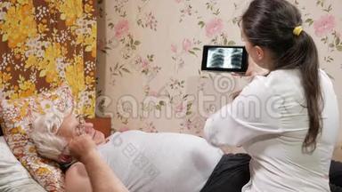 一位女医生在家看望病人。 它显示了平板电脑上X射线的结果.. 他躺在床上