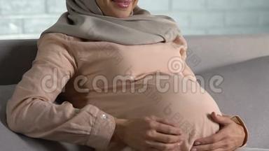快乐的阿拉伯孕妇抚摸着肚子，微笑着，做母亲，享受医疗保健
