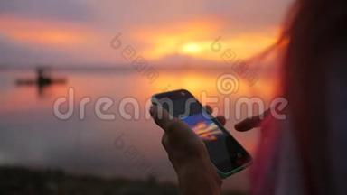 在渔人码头，年轻少女在手机上拍摄美丽日落的照片。 高清慢速运动。 泰国。