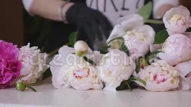 工作中的花商：女人做一束白色玫瑰和不同的花。 花商。 鲜花店。 准备花束