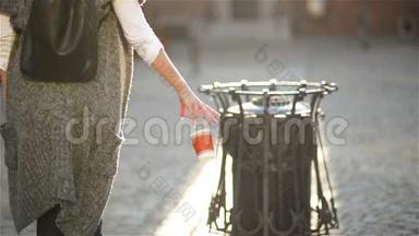 女人扔空纸咖啡杯附近回收站，城市背景。 回收利用、生态友好<strong>办法</strong>概念