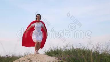 年轻的女人穿着红色的斗篷，表现着<strong>梦想</strong>。 女孩<strong>梦想</strong>成为超级英雄。 美丽的超级英雄