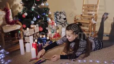 可爱的小女孩留着长长的头发，戴着圣诞礼物和蜡烛，给圣诞老人写了一封信