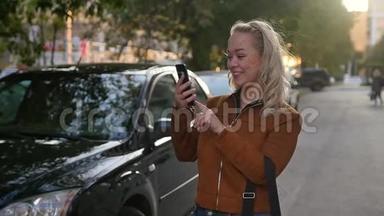 年轻快乐的女人在街上的智能手机上拍新照片。 在路上为社交网络做自拍的女孩