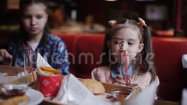 一个漂亮的小女孩喝果汁，在<strong>快餐</strong>里吃薯条。 <strong>快餐</strong>店
