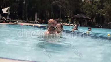年轻的爸爸和一个女儿在游泳池里玩耍和嬉戏
