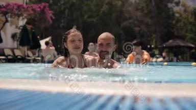 年轻的爸爸和一个女儿在游<strong>泳池里玩耍</strong>和嬉戏