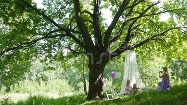 一家人在公园野餐-爸爸、妈妈和女儿在大树下