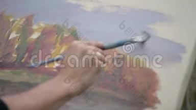 一位年轻而有创造力的艺术家在露天画布上画一幅画，一个人在画布上画一支画笔，这是一幅画