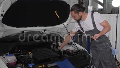 年轻英俊的机械师在汽车车间，靠近敞篷，专业服务汽车与平板电脑，