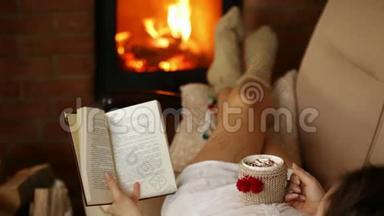 女人在沙发上放松，喝着热饮料和好书