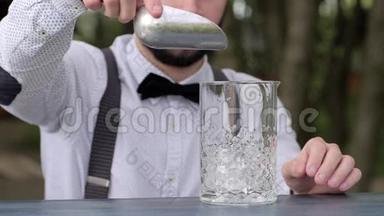 酒吧桌上的酒保把透明的冰块放进玻璃里，酒吧服务员把冰块放进新鲜空气里的玻璃里