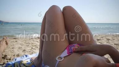 年轻的白种人白天躺在海边的沙滩上。 吸引人的臀部和腿的观点。