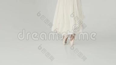 芭蕾舞女`的腿在尖鞋特写。 芭蕾舞演员穿着一件长而起伏的连衣裙跳芭蕾。 慢动作