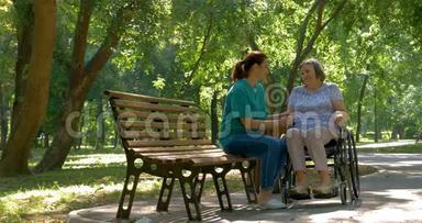 照顾者在户外轮椅上与残疾老年妇女交谈