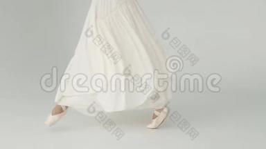 芭蕾舞女`的腿在尖鞋特写。 芭蕾舞演员穿着一件长而起伏的连衣裙跳芭蕾。 慢动作