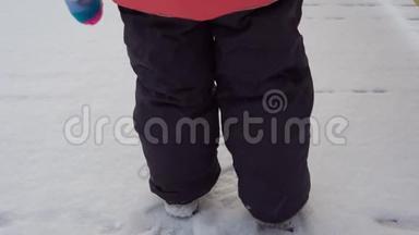 一个穿着<strong>暖</strong>和的衣服的孩子走过雪地，他的<strong>脚</strong>留下了痕迹。