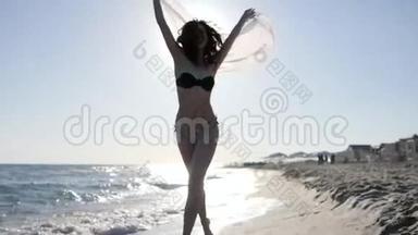 女人在背光下的海滩上奔跑，慢动作，穿着泳衣、背景沙子和大海的快乐女孩，沿着海滩奔跑，