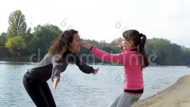 妈妈和女儿在河岸上。 妈妈在河边拥抱她的女儿。 家人在拥抱。 T T