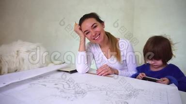 两个姐妹坐在桌子旁拿着Whatman纸，白猫躺在女孩身边。