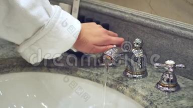 女人打开浴室水龙头，用自来水洗手
