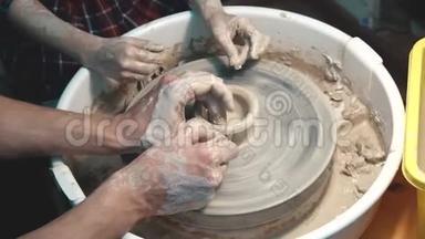 陶工教孩子做陶工`轮子.. 成人和儿童`双手特写。