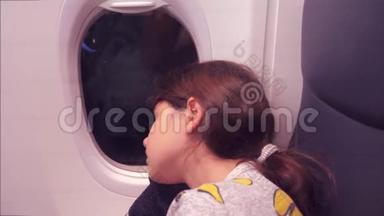 <strong>航空飞机</strong>概念。 坐在窗边的小女孩睡在飞机上。 夜间飞行的生活方式