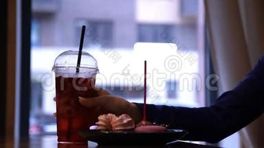 年轻迷人的女人坐在咖啡馆里喝一杯清爽的饮料。