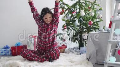 快乐的年轻漂亮女人把纸屑扔在窗边的圣诞树附近。 慢动作。 3840x2160