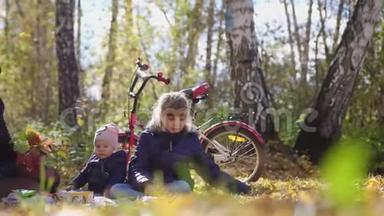 在一个阳光明媚的秋日，一个带着孩子的小家庭在公园野餐。 慢动作。 3840x2160。 4K.