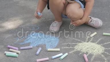 一个小女孩在沥青上画粉笔。 孩子在公园里晒太阳..