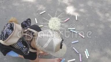 一个小女孩在沥青上画粉笔。 孩子在公园里晒太阳..