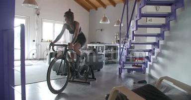 年轻的纹身骑自行车的妇女骑自行车在家里健身运动锻炼。 客厅<strong>家政</strong>培训.. 4公里