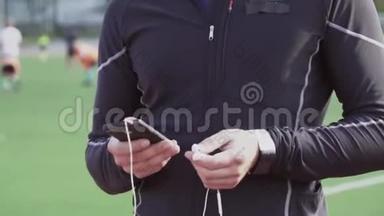 主题体育与健康.. 一个年轻的白人男子使用智能手机smarfton听耳机音乐。 技术