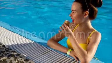 美丽的年轻女子穿着<strong>泳装</strong>，站在游泳池里吃冰淇淋