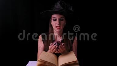 美丽的女人穿着黑色的女巫服装和<strong>帽子</strong>，手里拿着一个透明的<strong>魔法</strong>球，变魔术。 万圣节