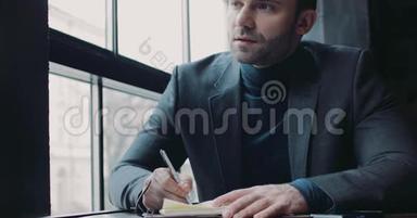 一个欧洲年轻人在窗户旁的咖啡馆©做笔记。 正式穿着。 商业生活，成功的生活方式.. <strong>作为</strong>一个