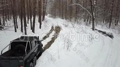 越野车6x6克服了一个大水坑上的土路在冬季森林。 非公路