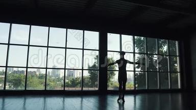 大窗户背景上芭蕾舞演员的剪影。 舞者踮起脚尖优雅地移动。 慢慢慢慢