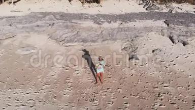 无人驾驶飞机看到年轻漂亮的黑发女人放松和喝椰子水站在海滩蓝色。