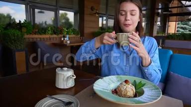 欧洲女孩在餐馆喝茶，然后慢慢地吃蛋糕。
