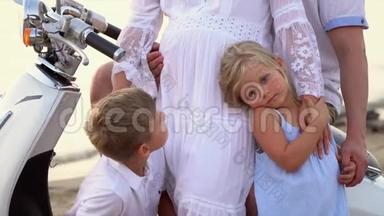 孩子们在海滩上拥抱怀孕的母亲。 亲密的家庭摆<strong>姿势拍照</strong>。