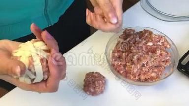 一个女人用膨松的糕点条包裹碎肉丸。 桌子旁边放着几条酥皮，还有一个剁碎的